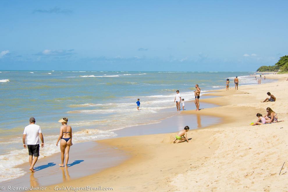 Imagem de famílias nas areias e na beira da Praia de Apaga Fogo.